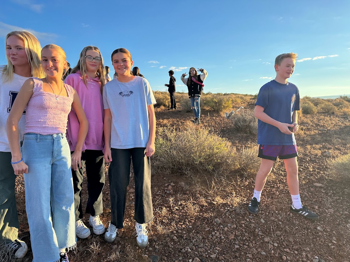 Five seventh grade girls pose for the camera during the rock hunt while one seventh grade boy continues his search.