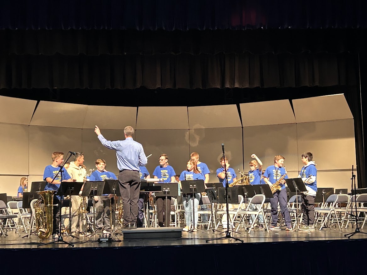 Mr. Szymanski conducts the TIS Intermediate Band as they perform during a concert on stage.