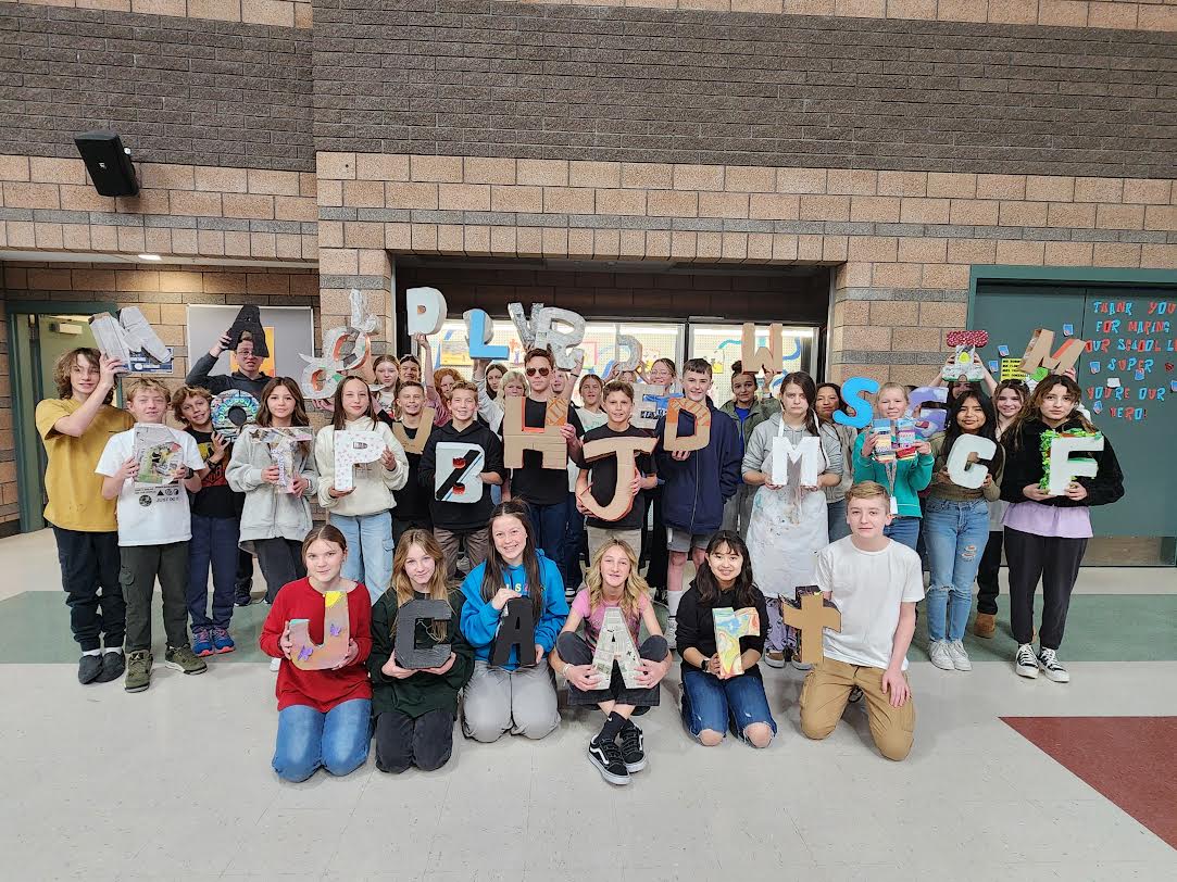 Ms. Bulkley's art students show off their 3D letters posing in front of the trophy case in the commons area.